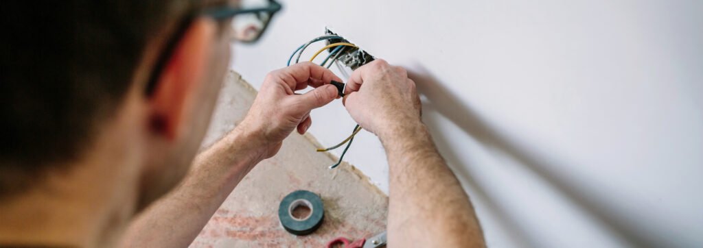electrician wrapping cable with electrical tape on the electrical installation of a house